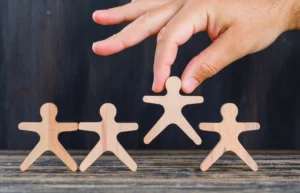 Hand hebt Holzfigur aus Reihe, Einbürgerung Berlin Dauer