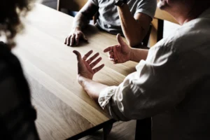Personen diskutieren am Tisch, Aussage gegen Aussage Sexualstrafrecht