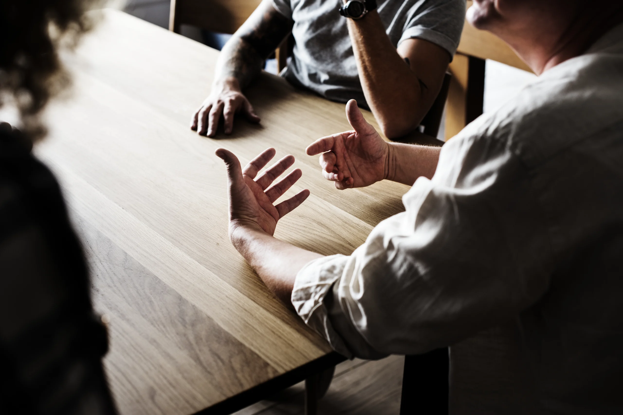 Personen diskutieren am Tisch, Aussage gegen Aussage Sexualstrafrecht