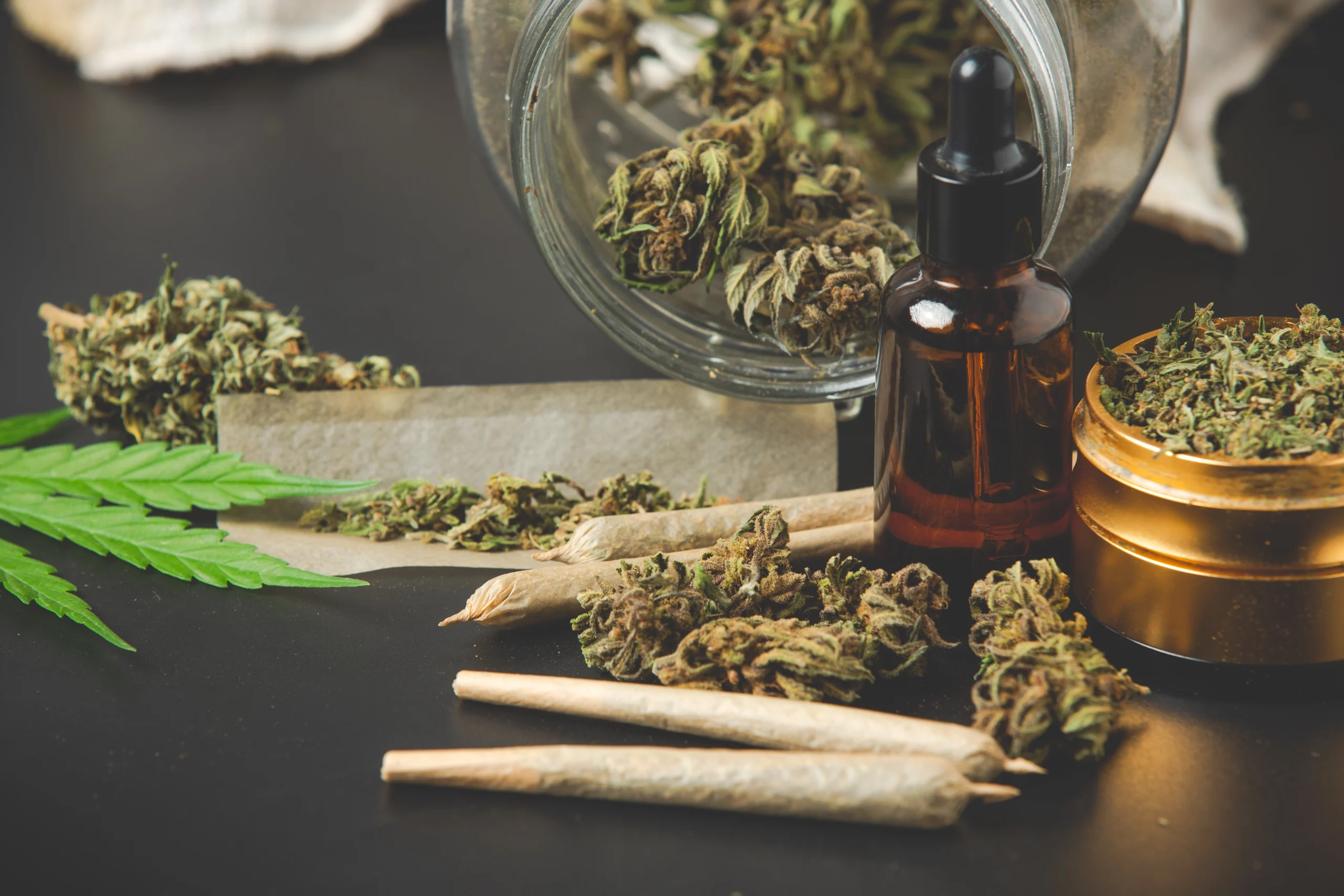 Cannabisblüten, Joints und Cannabisöl auf dunklem Untergrund, Cannabis Eigenbedarf Strafrecht Berlin