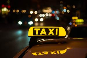 Beleuchtetes Taxischild auf einem Autodach bei Nacht in der Stadt, Symbolbild für das Koks-Taxi und den Kokainhandel per Lieferdienst